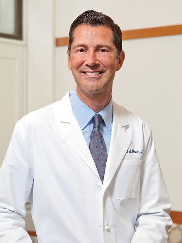 Dr. Dan Monti smiling in white doctor's coat