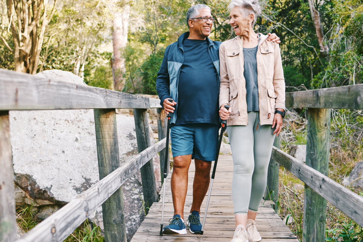 Senior man and woman smiling and hiking together to promote a long, healthy life